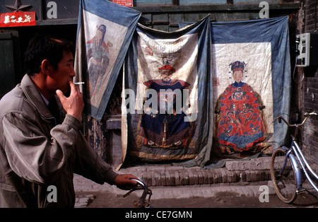 Pedestrian walks past figurines in the city of Ping Yao officially Pingyao Ancient City in central Shanxi, China Stock Photo