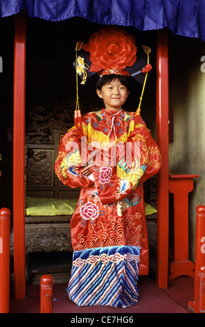 Young Chinese girl wears rented Qing Dynasty style wedding dress costume while visiting Tiantan Park in Beijing China Stock Photo