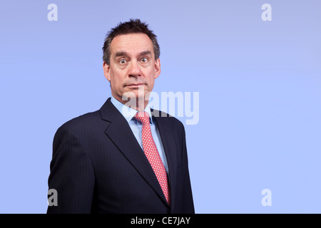 Surprised Shocked Handsome Business Man in Suit on Blue Background Stock Photo