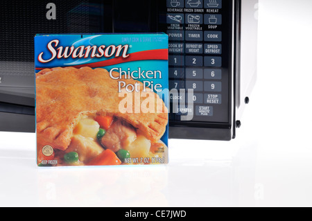 Swanson frozen chicken pot pie tv dinner in packaging in front of microwave on white background USA Stock Photo
