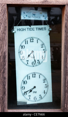 Two clock faces show High Tide Times, displayed behind a window on the South Quay, King's Lynn. Stock Photo