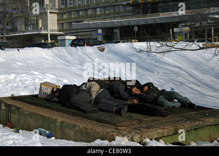 Homeless people sleeping on a warm air vent in Moscow, Russia Stock Photo