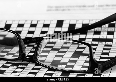 A pair of reading glasses lying upturned on top of a large incomplete crossword Stock Photo