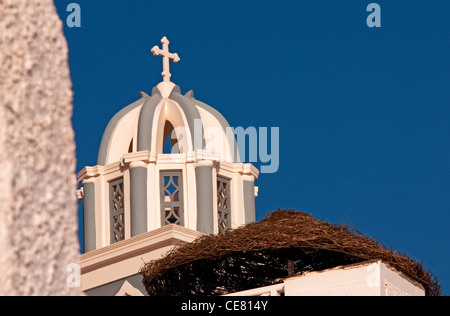 Dome of church with cross near a thatch resort umbrella, Firostefani, Santorini, Greece Stock Photo