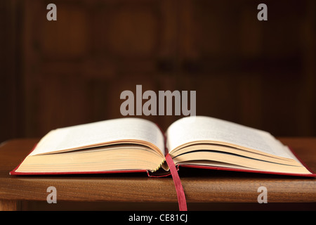 Close up of an open red book on an oak table with blurred background Stock Photo