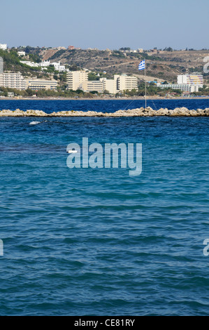 A solitary Greek flag flying on a small spit of land in the bay at Faliraki Stock Photo