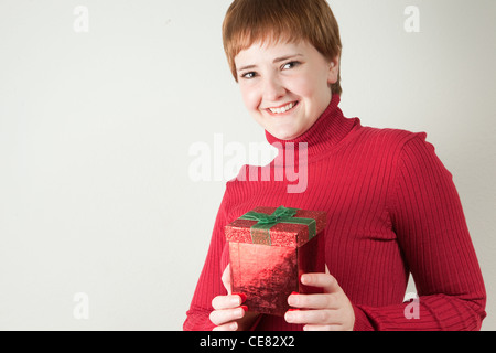 Studio portrait of redhead woman holding a red gift box Stock Photo