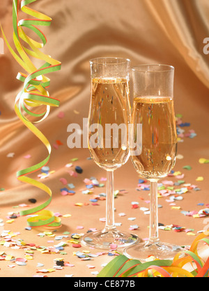 carnival scenery with filled stemware glasses and accessories in floating fabrics back with streamers and confetti Stock Photo