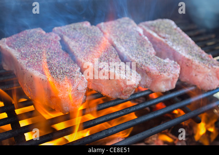 Seasoned beef strip loin steaks grilled over hot fire barbecue pit Stock Photo