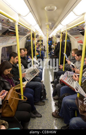 Commuters on underground train reading newspapers London United Kingdom ...