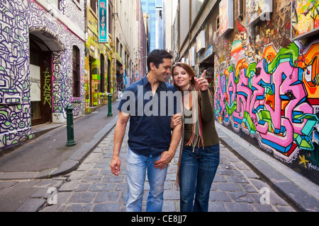 Young couple walking in city laneway, holding hands and looking at street art. Hosier Lane, Melbourne, Victoria, Australia Stock Photo