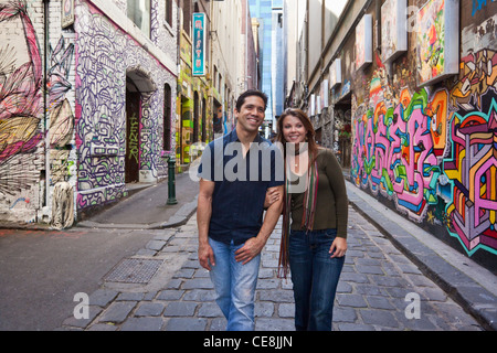 Young couple walking in city laneway, holding hands and looking at street art. Hosier Lane, Melbourne, Victoria, Australia Stock Photo