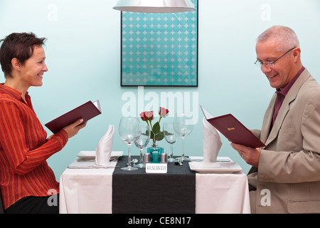Photo of a mature couple sitting in a restaurant reading the menu