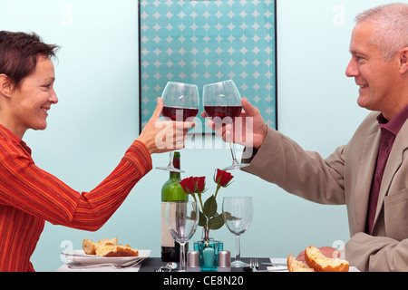 Photo of a mature couple toasting their glasses of red wine whilst sat in a restaurant Stock Photo