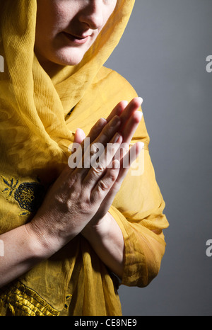 Woman wearing Yellow Shawl with Hands in Devotion Stock Photo