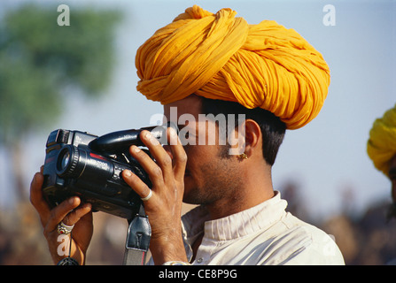 HMA 81191 : indian man in yellow turban looking through video movie camera pushkar fair rajasthan india Stock Photo