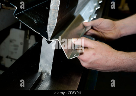 A worker at a metal sheet factory in Coventry, United Kingdom, machine bending a sheet of metal. Stock Photo