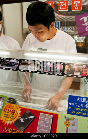 Stall selling traditional Korean sweets with a young men demonstrating how they are made to customers, Insadong, Jongno-Gu Stock Photo
