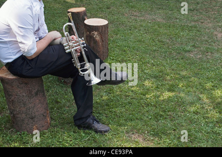 Musician resting on tree trunk stool Stock Photo