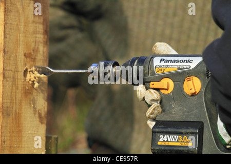 South Downs National Park Authority volunteer volunteers ranger rangers working installing a new gate drill drilling hole wood.. Stock Photo