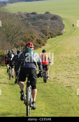 Young people cycling on mountain bikes bicycles off road in a field trail bridleway South Downs National Park Stock Photo