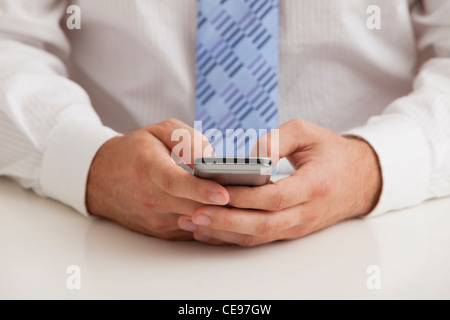 Studio shot of businessman text-messaging, midsection Stock Photo