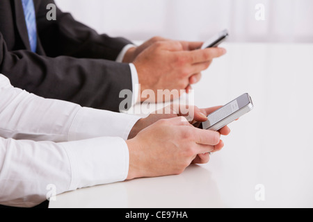 Studio shot of business people using cell phones, midsection Stock Photo