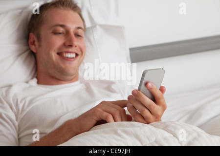 USA, Illinois, Metamora, Young man text-messaging in bed Stock Photo