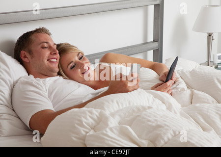 USA, Illinois, Metamora, Young couple text-messaging in bed Stock Photo