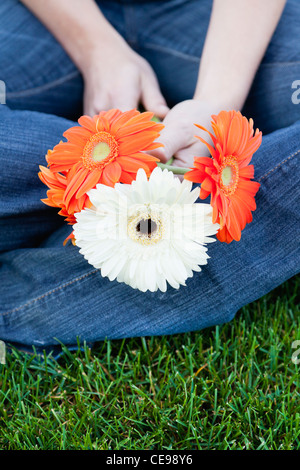 USA, Illinois, Metamora, Close-up of young woman sitting on grass, holding flowers Stock Photo