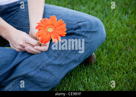 USA, Illinois, Metamora, Close-up of young woman sitting on grass, holding flower Stock Photo