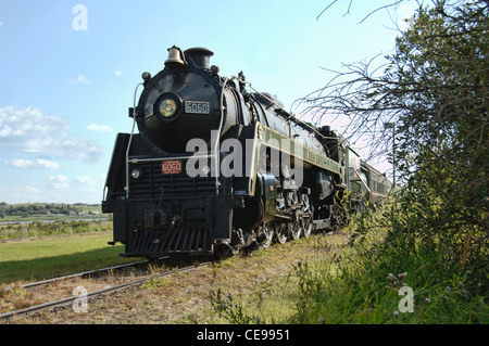 An old steam locomotive stopped on railway tracks. Stock Photo
