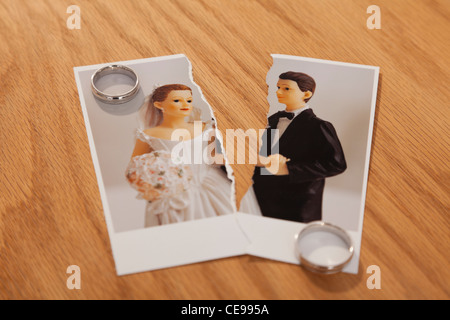 Studio shot of photo of bride and groom figurines torn in half and wedding rings Stock Photo