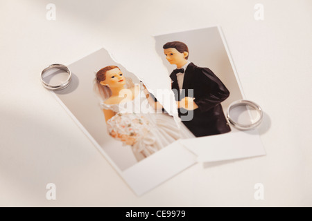 Studio shot of photo of bride and groom figurines torn in half and wedding rings Stock Photo