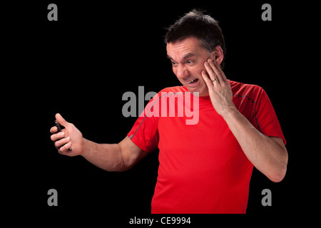 Middle Aged Man with horrified expression looking at phone in shock black background Stock Photo