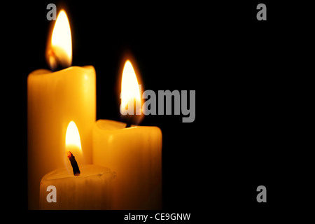 Three burning candles over a black background Stock Photo