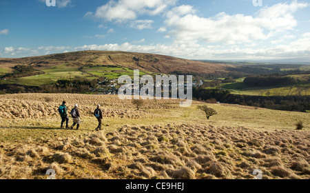 Winter walkers walking off Meiklehom Hill lookng down on the town of Langholm on the Scottish border with Whita Hill behind Scot Stock Photo