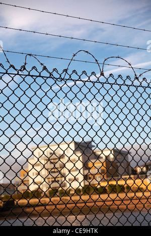 Looking through barb wired fence at out of focus buildings in the distance behind at Poole in December Stock Photo