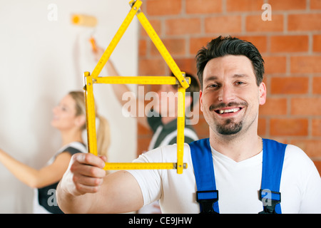 Three people - one woman and two men - renovating an apartment and having lots of fun Stock Photo