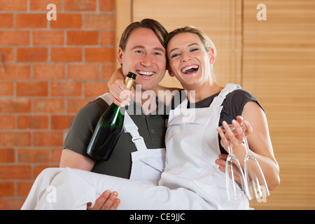 Young couple moving in new flat doing renovation and painting, celebrating their new home with sparkling wine Stock Photo