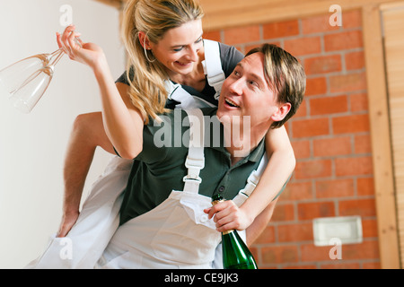 Young couple moving in new flat doing renovation and painting, celebrating their new home with sparkling wine Stock Photo