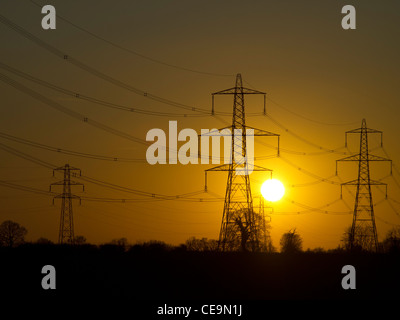 The sun setting behind electricity pylons. Stock Photo