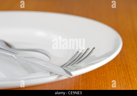 Knife and fork on single white plate Stock Photo