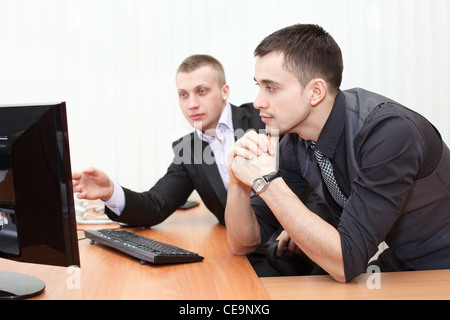 Two Caucasian business men working together at computer. Looking at monitor in office Stock Photo