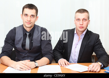 Smiling Caucasian business men working together at office and looking at camera Stock Photo