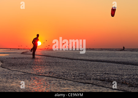 A man on the beach in Essaouira watching a kite surfer at sunset, Morocco Stock Photo