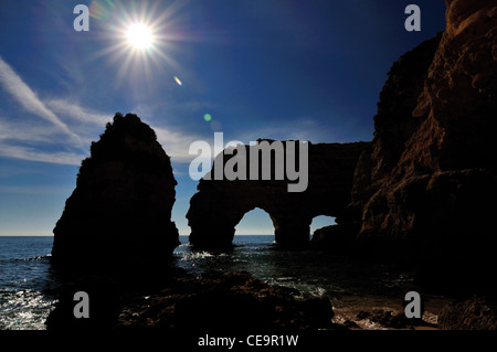 Portugal, Algarve: Rocky silhouette of Praia da Marinha against the midday sun Stock Photo