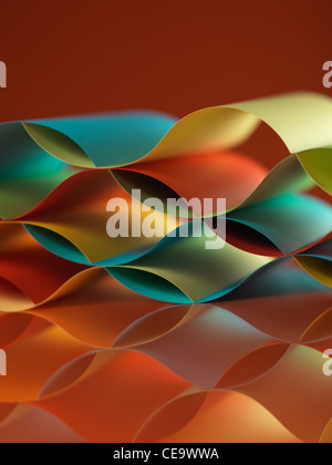 background macro image of colorful origami pattern made of curved sheets of paper, with mirror reflexion, on orange background Stock Photo