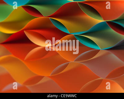 background macro image of colorful origami pattern made of curved sheets of paper, with mirror reflexion, on orange background Stock Photo