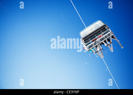 Ski lift carrying unrecognizable skiers up to the clear blue sky Stock Photo
